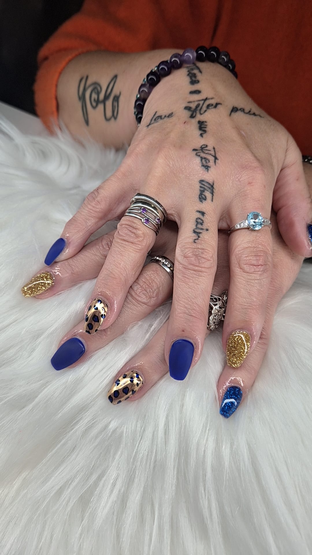 Blauwe, gouden en panterprint nagels op een witte vacht
